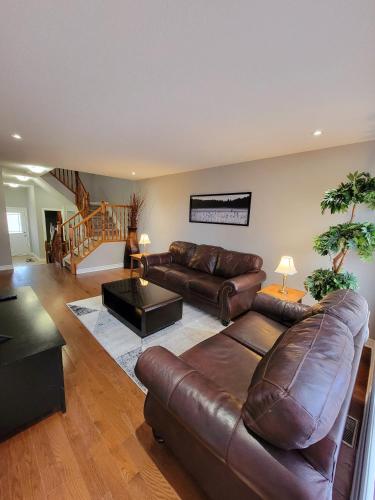 a living room with a leather couch and a table at Cozy 3 bedroom town house 20 min from Ottawa down town and airport in Ottawa