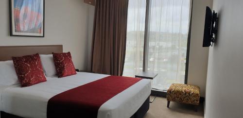 a hotel room with a bed and a large window at Ramada Suites by Wyndham Manukau in Auckland