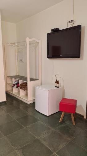 a living room with a tv and a red stool at Pousada Casa Doce Vida in Águas de Lindóia