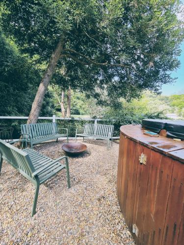 two benches and a fire pit in a yard with a tree at Rock Davis Luxury Beachouse - 100mtrs to Beach in Patonga