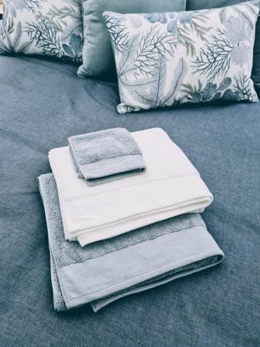 a pile of towels sitting on a bed with pillows at Rock Davis Luxury Beachouse - 100mtrs to Beach in Patonga