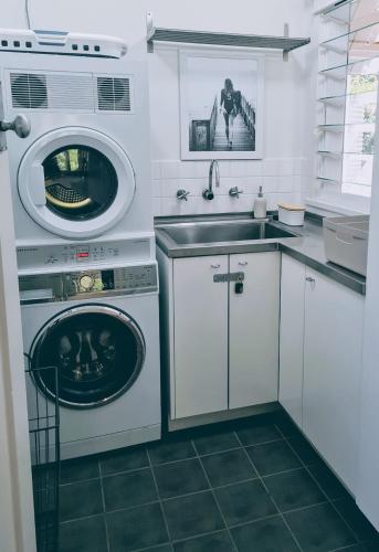 a kitchen with a washing machine and a sink at Rock Davis Luxury Beachouse - 100mtrs to Beach in Patonga