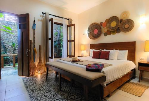 a bedroom with a bed with a bench in it at Le Muuch Hotel Boutique in Valladolid