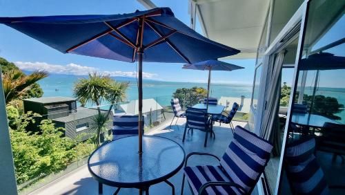 a table with chairs and an umbrella on a balcony at Kimberley Three - Nelson Waterfront Penthouse in Nelson