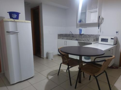 a kitchen with a table and two chairs and a microwave at ÁGUAS da SERRA - RIO QUENTE in Rio Quente
