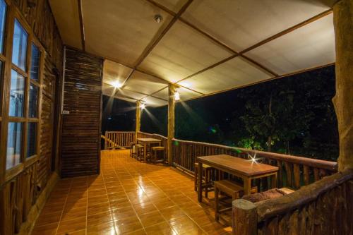 a porch with tables and chairs on a deck at night at บ้านสวนศรเพชร in Phetchabun