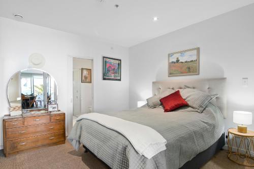 a bedroom with a bed and a dresser and a mirror at Wakefield Wonder - Nelson Holiday Apartment in Nelson