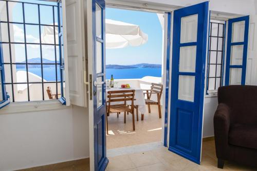 Habitación con puerta azul y mesa con sillas. en Top Oia, en Oia
