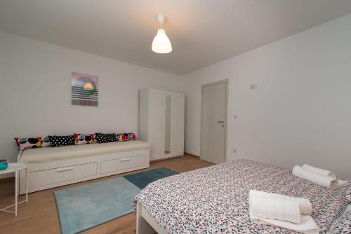 a white bedroom with a bed and a bench at House POLUS in Trogir