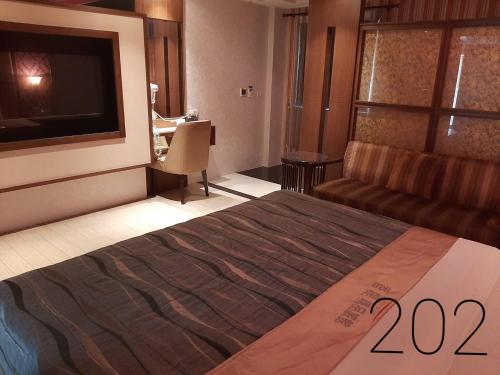 a bedroom with a bed and a couch and a television at Chateau Motel & Spa (Daliao) in Daliao