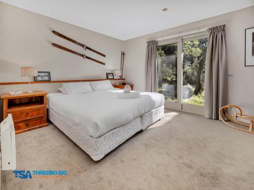 a bedroom with a large white bed and a window at Ramshead Creek 1 in Thredbo