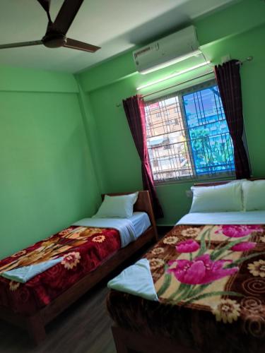 2 camas en una habitación con paredes verdes y ventana en Harry Guest House & Restaurant en Pokhara