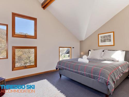 a bedroom with a bed and two windows at Ramshead Creek 2 in Thredbo