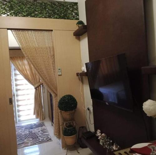 uma sala de estar com televisão e janela em EMSMAR 908 Wind Residences Tagaytay em Tagaytay