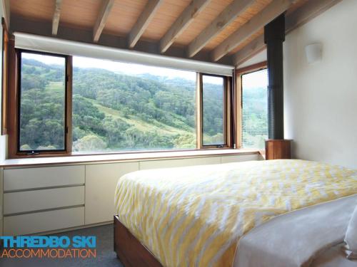 sypialnia z łóżkiem i dużym oknem w obiekcie Sneznik w mieście Thredbo
