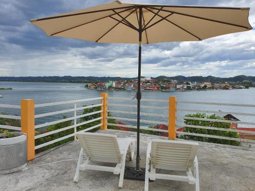 a table with two chairs and an umbrella next to the water at APARTHOTEL VISTA LAGO in Flores
