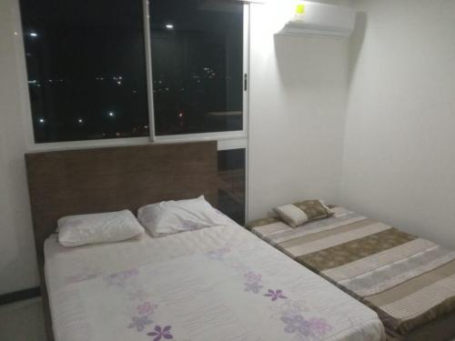 ein Schlafzimmer mit zwei Betten und einem Fenster in der Unterkunft Magnífico apartamento, Santa Marta sector Irotama in Santa Marta