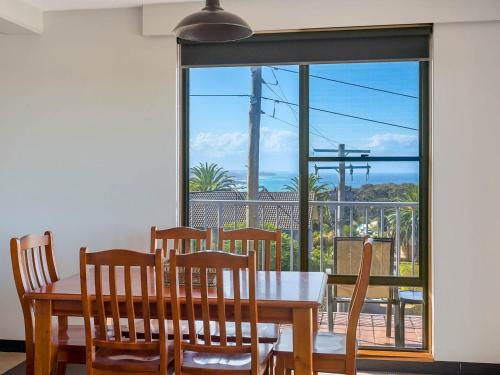 
a dining room table with chairs and a window at Sheridan Court on Wagonga in Narooma
