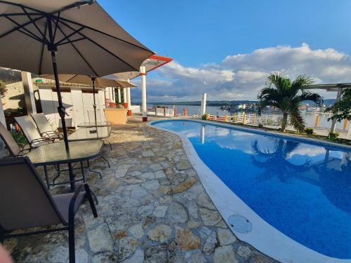 a swimming pool with a table and an umbrella at APARTHOTEL VISTA LAGO in Flores