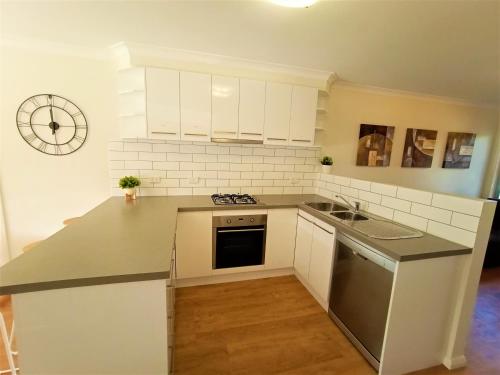 uma cozinha com armários brancos e uma bancada em My Abode in Albury em Albury