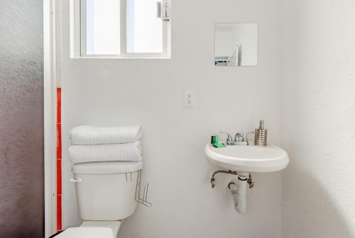a white bathroom with a toilet and a sink at RCH Suite in Mexico City