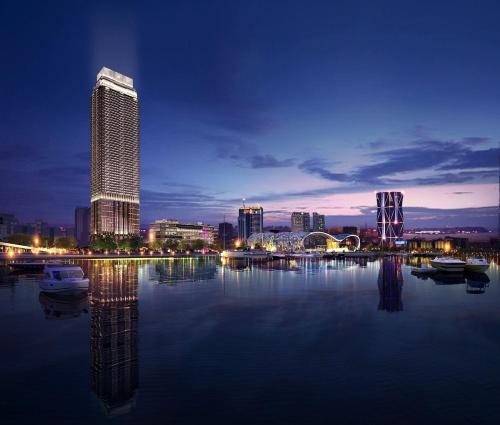 InterContinental Kaohsiung, an IHG Hotel في كاوشيونغ: أفق المدينة في الليل مع هيئة مياه