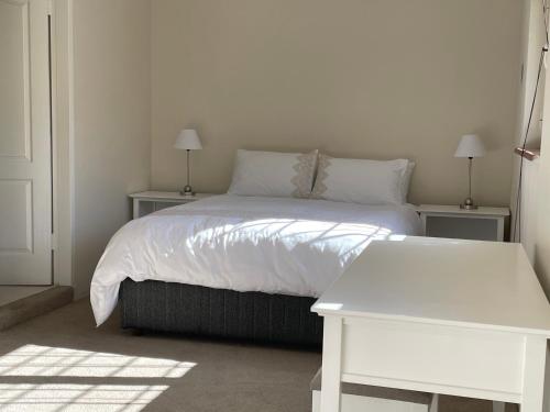 una camera da letto con un letto con lenzuola bianche e due tavoli di BaobabSuites a Johannesburg