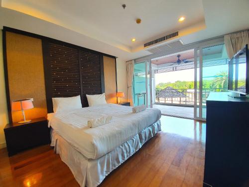 a bedroom with a large bed and a balcony at Spacious apartment with Ocean view in Panwa in Phuket Town