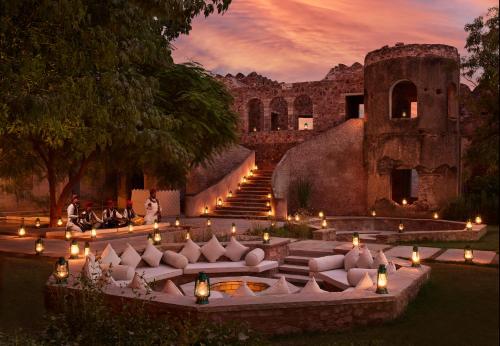 a group of people sitting in a courtyard with candles at Six Senses Fort Barwara Sawai Madhopur in Sawāi Mādhopur