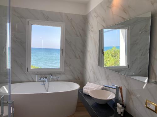 a bathroom with a tub and a sink and a mirror at Villa Blanca del mar in Quartu SantʼElena