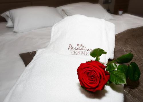 a red rose on a white towel on a bed at Terme Paradiso - Hotel Paradiso in Dobova