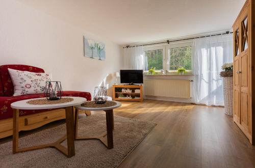 ein Wohnzimmer mit einem roten Sofa und 2 Tischen in der Unterkunft Landferienwohnung Simon in Schmallenberg