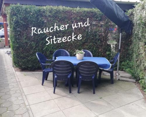 einem blauen Tisch mit vier Stühlen und einem Sonnenschirm in der Unterkunft Auerandzimmer in Nienhagen