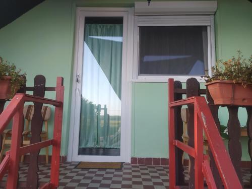 a white door with a window and a potted plant at Etus Vendégház in Balatonfenyves