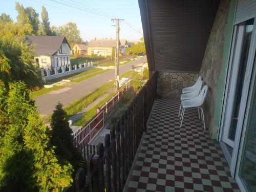 a porch with a checkered floor and a white chair at Etus Vendégház in Balatonfenyves