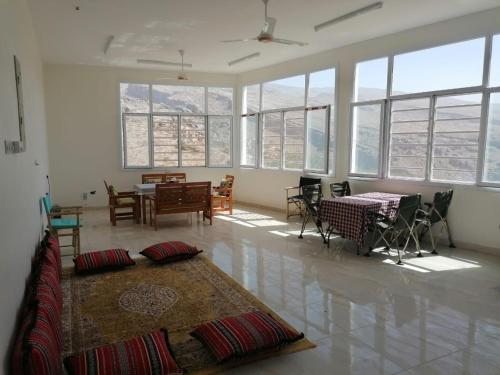 a living room with a table and chairs and windows at Misfah View in Misfāh