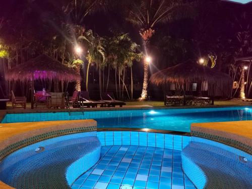 a swimming pool at night with tables and umbrellas at PX POOL VILLA PATTAYA in Nong Prue