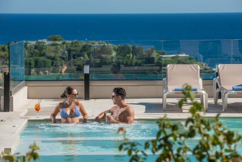 a man and a woman sitting in a swimming pool at Irida Hotel Agia Pelagia in Agia Pelagia