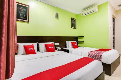 two beds in a room with green walls and red pillows at Ct Hotel in Sitiawan