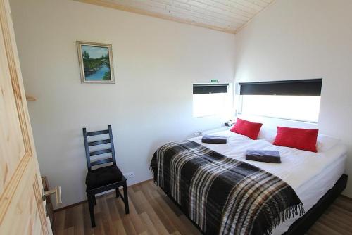 een slaapkamer met een bed met rode kussens en een stoel bij Blue View Cabin 1A With private hot tub in Reykholt