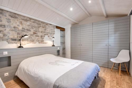 ein Schlafzimmer mit einem weißen Bett und einem weißen Stuhl in der Unterkunft MACÉDOCY Maison de charme au cœur du Village in Sainte-Marie-de-Ré