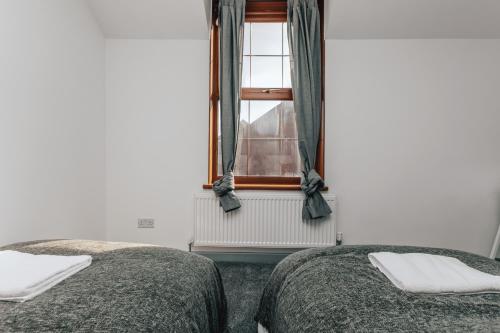 two beds in a room with a window at HOMELY 3BD TOWNHOUSE w 2WCs 15MINS TO BHAM &WOLV in Tipton