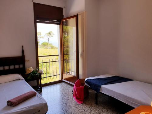 a room with two beds and a window with a balcony at Xaloc, apartament amb vistes a mar M4 in Port de la Selva