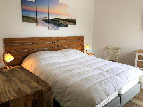 a bedroom with a large bed with four paintings on the wall at PERLIERES T2 lumineux vue bassin parking wifi in Arcachon