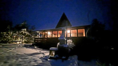 a house with lights on in the snow at night at Sodyba Vilagio in Alanta