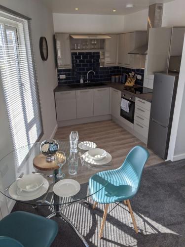 a kitchen with a glass table and chairs and a kitchen with a refrigerator at Stylish penthouse apartment in Ramsgate