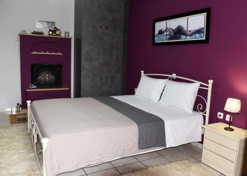 um quarto com uma cama branca e uma parede roxa em Alesta Apartment em Trikala