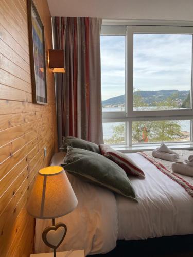 um quarto com uma cama e uma grande janela em Appart'Hôtel LIDO au bord de l'eau em Gérardmer