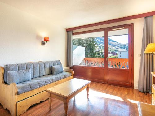un salon avec un canapé et une grande fenêtre dans l'établissement Vacancéole - Résidence L'Edelweiss, à Les Deux Alpes