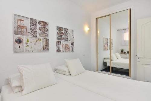 a white bedroom with two beds and a mirror at Beach Apartment Playa del Cura 4 in Playa del Cura